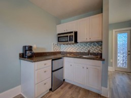 modern motel kitchen area with coffee maker, microwave, sink, and mini fridge